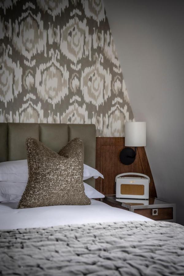 The Marylebone Hotel Лондон Экстерьер фото A bedroom with a bed, a nightstand, a lamp, and a pillow